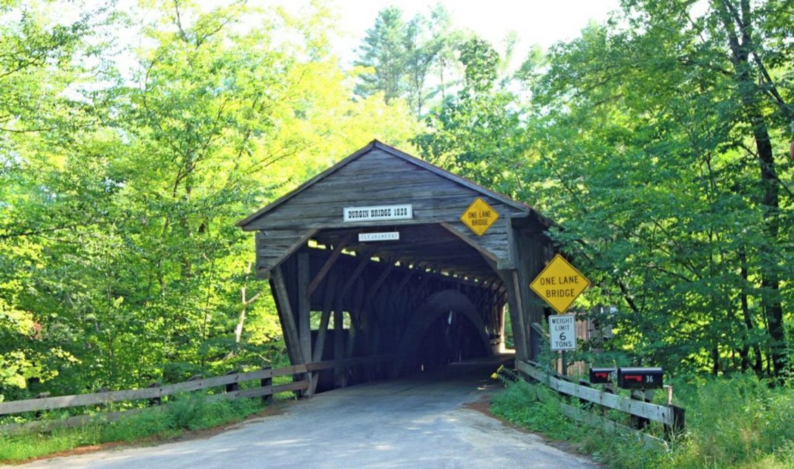 A covered bridge with a sign indicating 'Dunghill Bridge 1826' and a 'ONE LANE BRIDGE' warning.