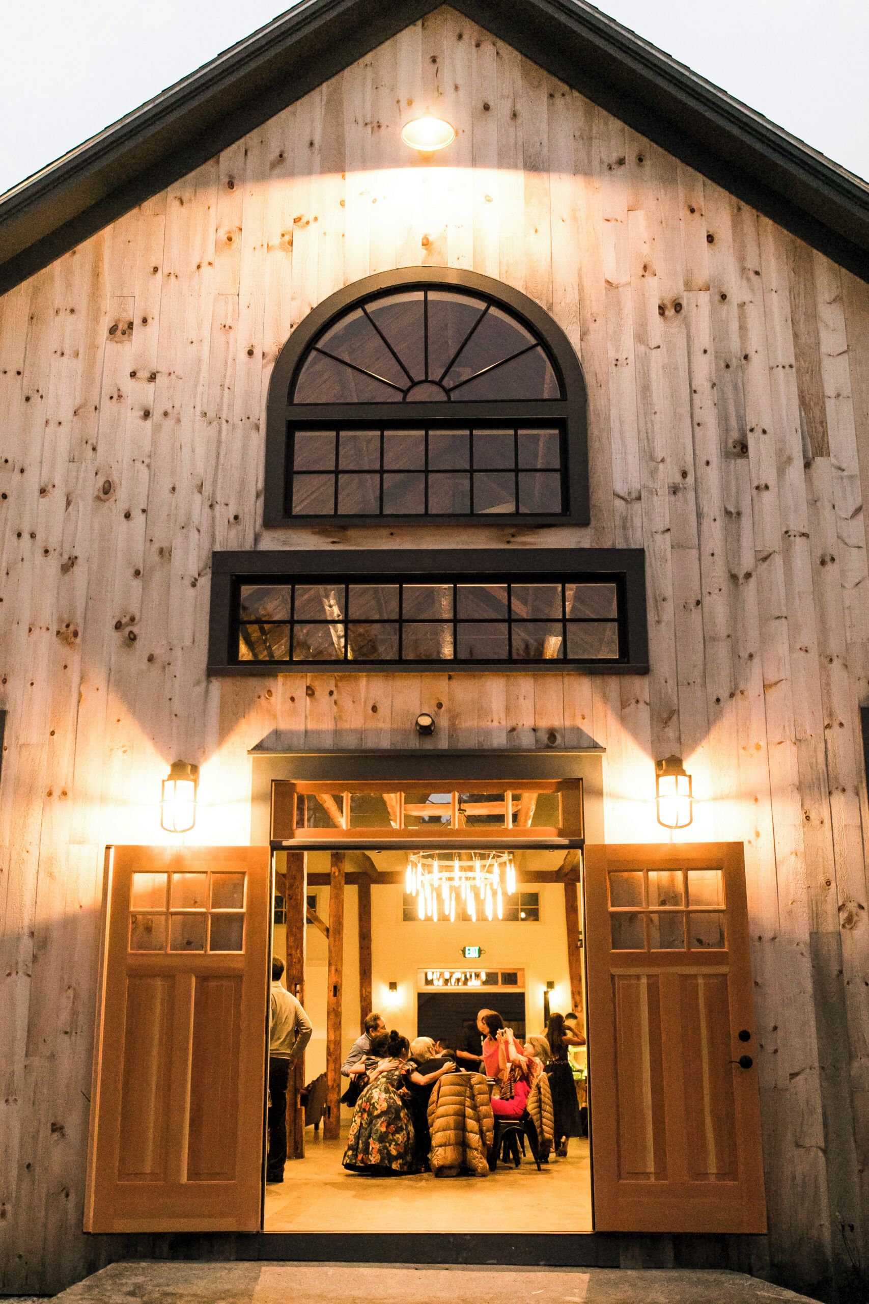 A wooden barn-style building with a large arched entrance and two side doors.