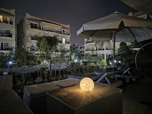 A rooftop lounge area with seating, a decorative light, and a view of surrounding buildings. - Stay Savvy in Sharm | Luxe 2BR & Chill Terrace - The View - Nabq - Sharm (South Sinai Governorate)