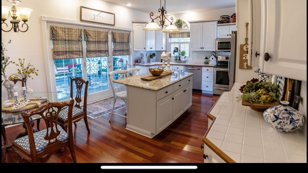 A kitchen with a central island, white cabinetry, a dining area with chairs, and a view through the glass door. - RuneStone Ranch: on Lake Cumberland, Upper Level, Russell Springs (Russell Springs)