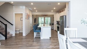 Una cocina amplia con una isla central, armarios blancos y un refrigerador de acero inoxidable.