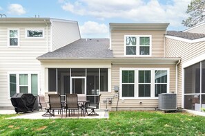 Ein Wohnhaus mit Terrasse, Sitzgelegenheiten im Freien und einer Klimaanlage.