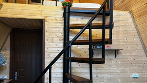 Un intérieur en bois avec un escalier en colimaçon, une porte et un petit tabouret.
