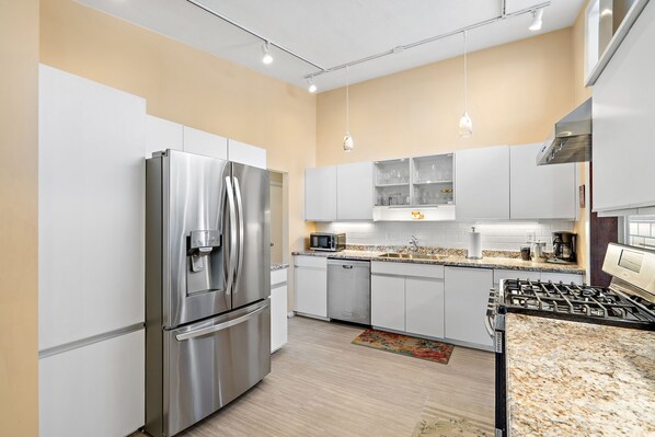 A modern kitchen with stainless steel appliances, white cabinetry, and a granite countertop. - Spacious Retreat Near Boston with AC, Roku, Deck, BBQ Grill + Pet Friendly! (Framingham)