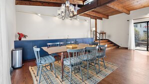 A spacious dining area with a wooden ceiling, a chandelier, and a blue upholstered chair. - Spacious Retreat Near Boston with AC, Roku, Deck, BBQ Grill + Pet Friendly! (Framingham)