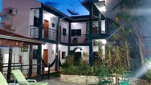 A multi-story building with a pool, outdoor seating, and a garden. - Pousada papaya (Bonito)