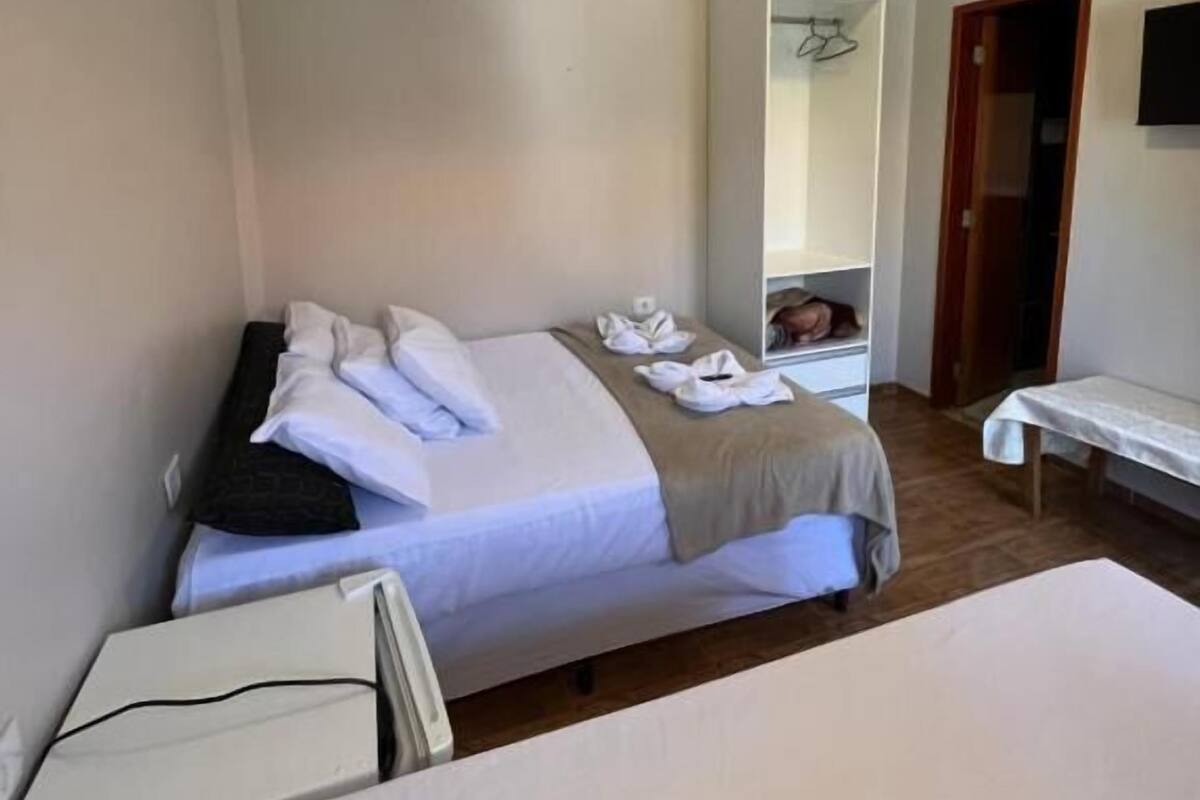 A hotel room with a bed, bedside table, and a mirror.