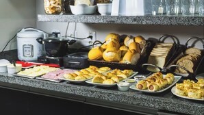 A buffet setup with various food items, including rolls, pastries, and sliced meats. - Pousada papaya (Bonito)