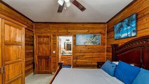 Ein Zimmer mit Holzwänden, einem Bett, einem Deckenventilator und einem Gemälde.