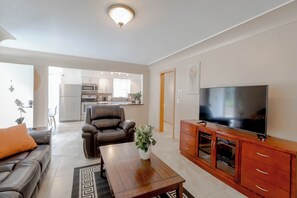 A modern living room with a sofa, a coffee table, a TV, and a kitchen in the background. - 907- Walk to Mayo St Mary Hospital 4 bed/2 bath 2 living rooms, Laundary/Parking (Rochester)