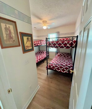 A room with bunk beds, a ceiling fan, and framed pictures on the wall. - Peaceful cottage centrally located. 8 min walk to beach via scenic walkway, (Oak Island)