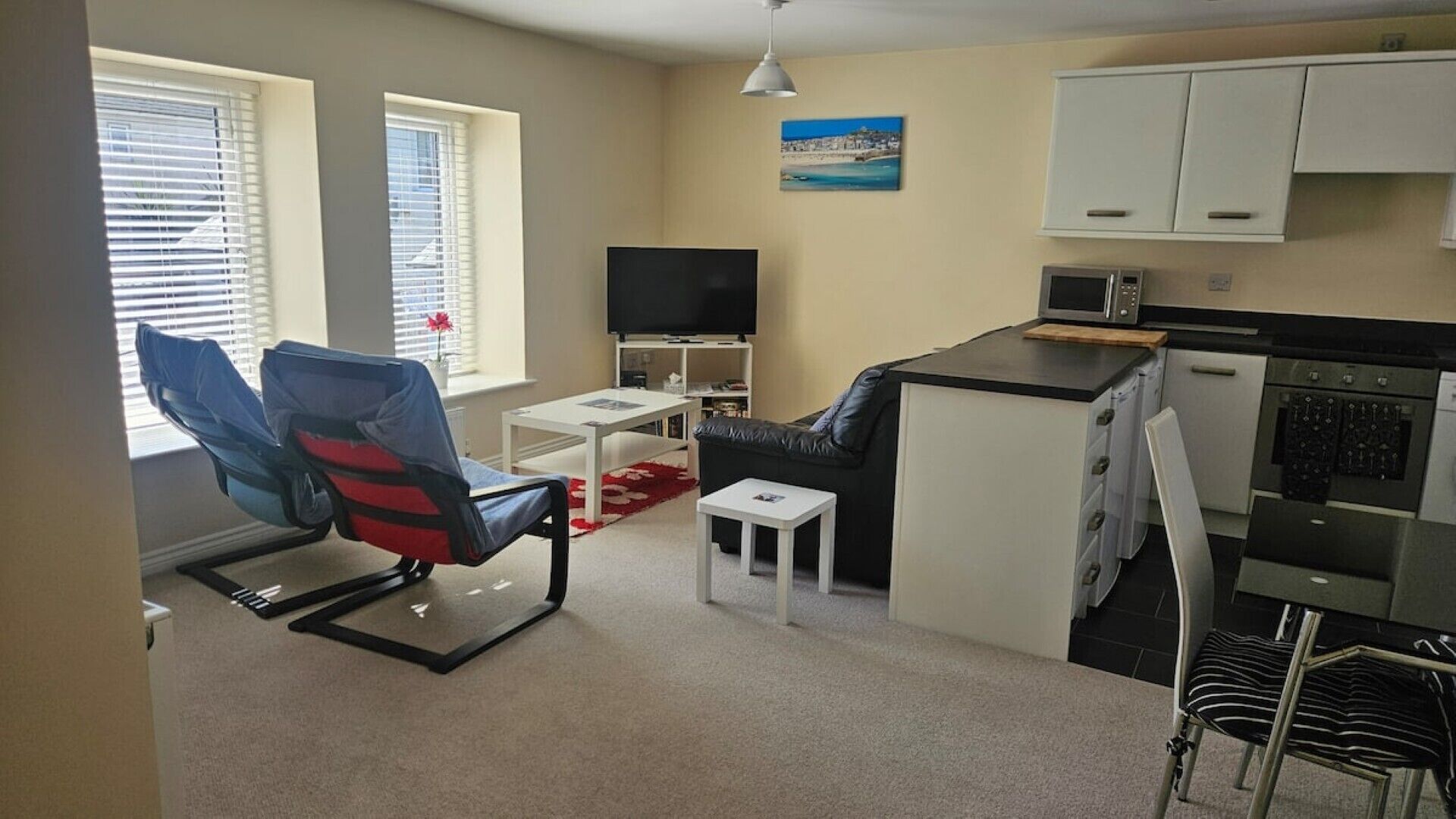 A compact living space with a sofa, TV, kitchenette, and a dining area.
