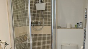 Ett badrum med en dusch som är avskärmad med glasväggar, en vit toalett och ett handfat.