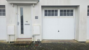 En byggnad med en vit dörr, två garageportar och en liten skylt med siffran 38.