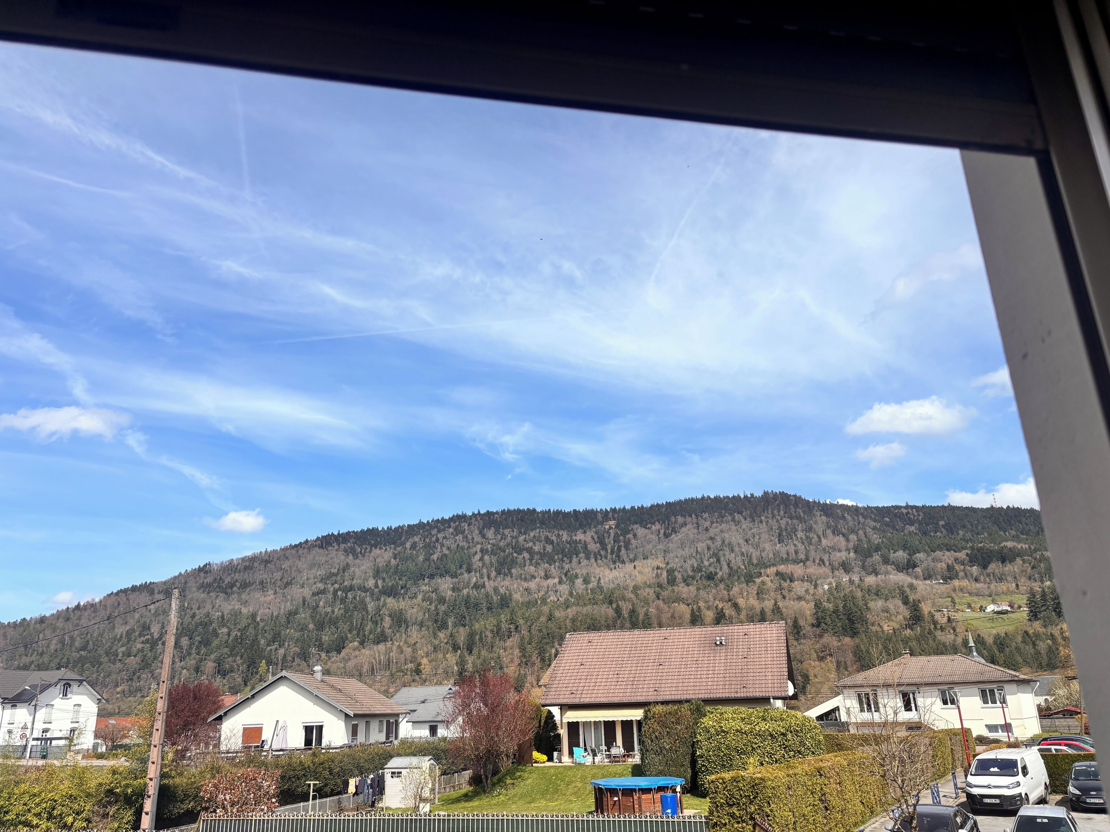 Un quartier résidentiel avec des maisons, un ciel dégagé et une colline en arrière-plan.