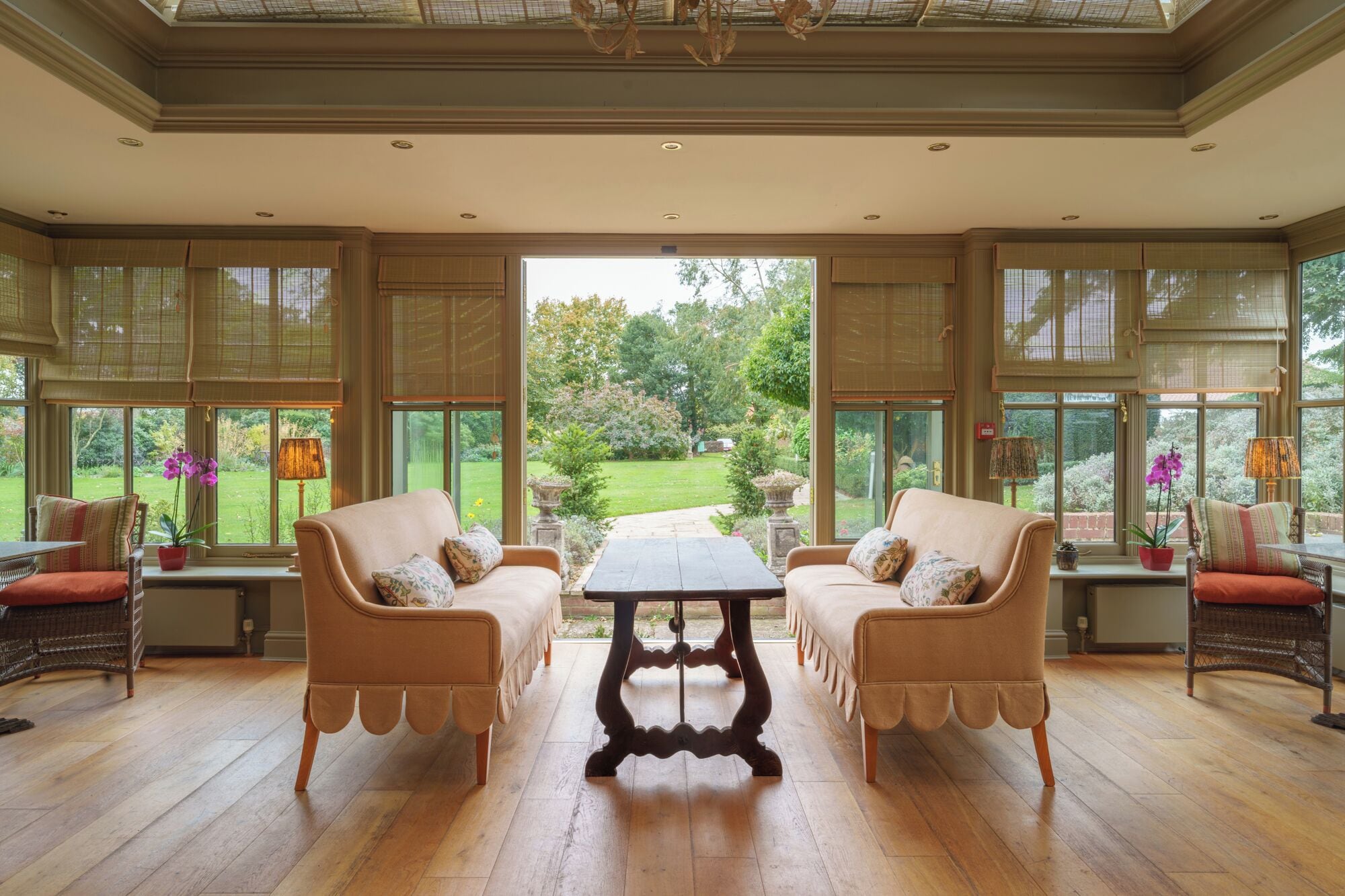 Amplia habitación con un ventanal grande, dos sofás, una mesa y vistas a un jardín.
