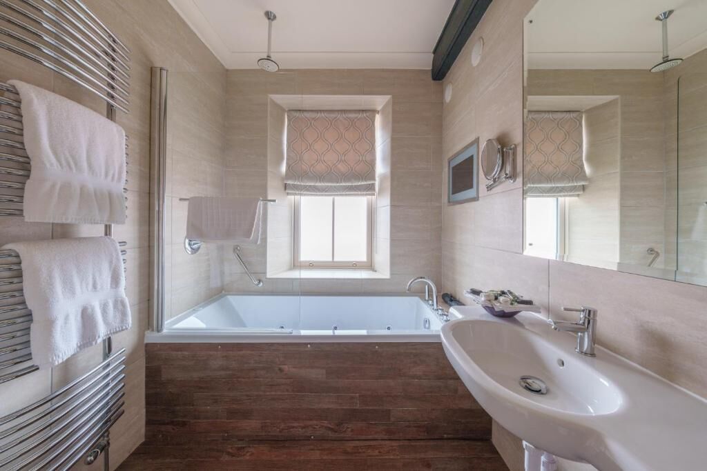 A modern bathroom with a bathtub, a sink, and a large mirror.