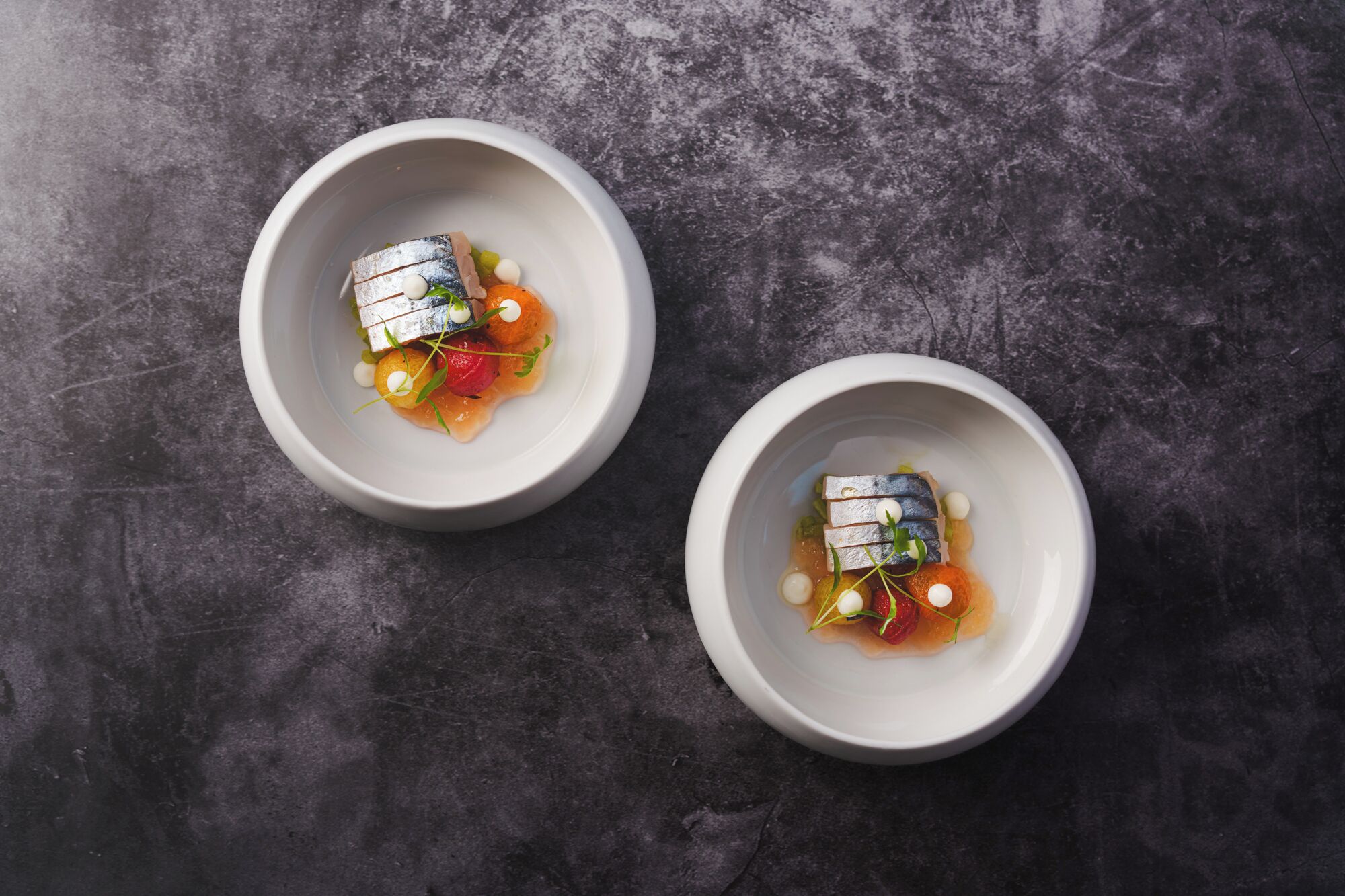 Two white bowls on a textured surface.