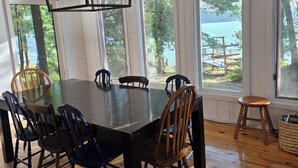 Ein Esszimmer mit großem Tisch, Stühlen und einer Hängelampe.