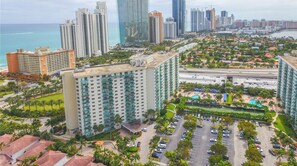 Un hotel moderno de muchas plantas, con estacionamiento y vistas al océano y al horizonte de la ciudad.