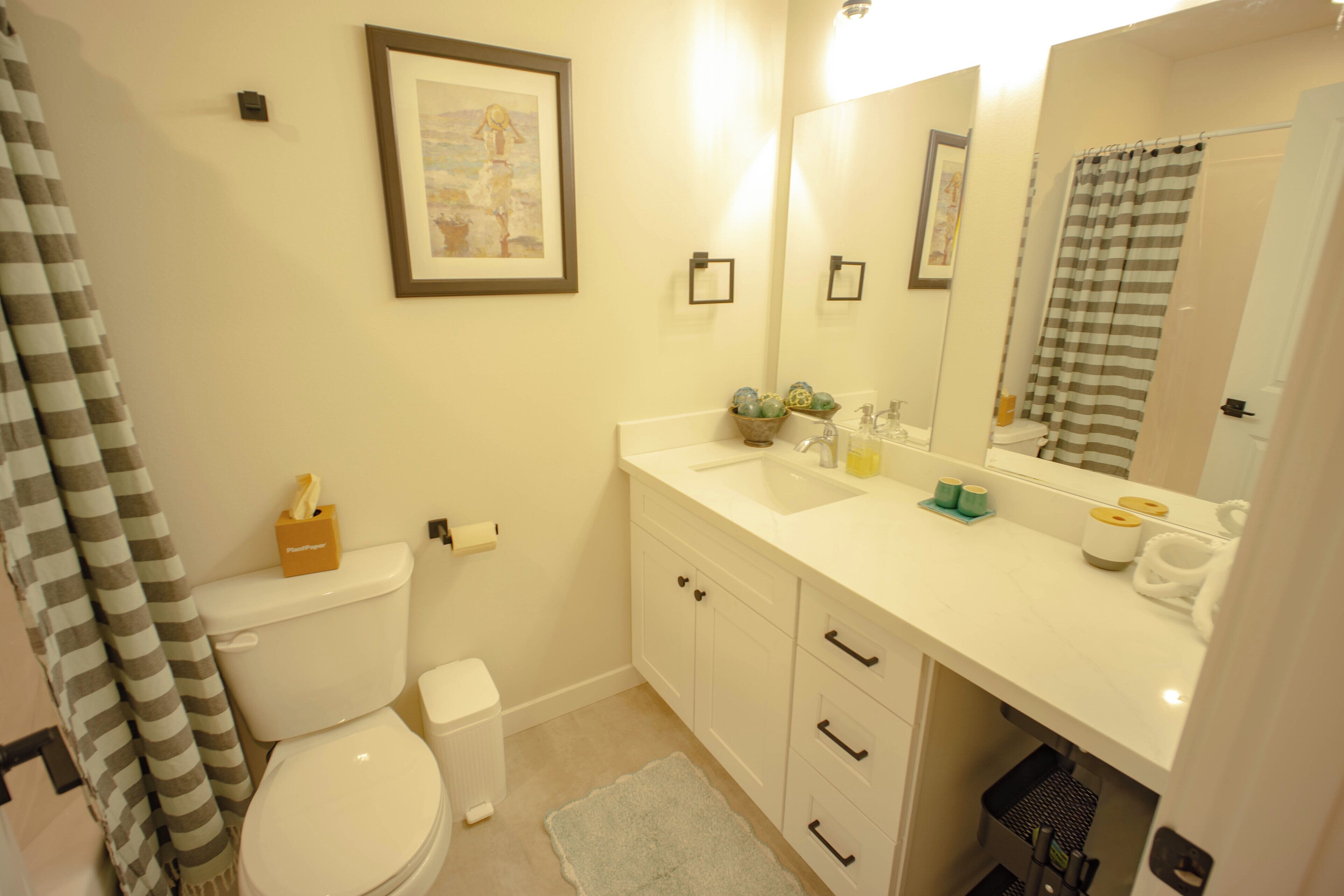 A bathroom with a toilet, sink, mirror, and towel rack.