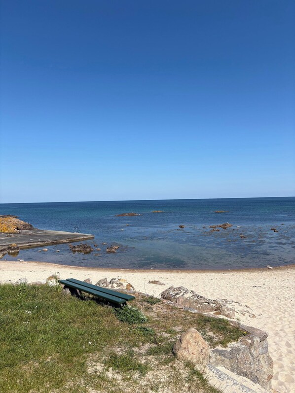 A beach with a concrete pier, a green bench, and clear blue water. - Lovely holiday apartment near centre (Allinge)