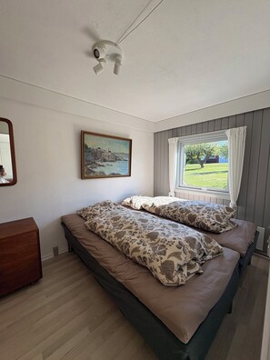 A bedroom with a bed, a painting, a window with curtains, and a ceiling fan. - Lovely holiday apartment near centre (Allinge)