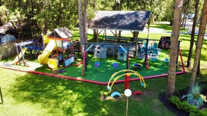 A playground with slides, swings, and a covered play area. - Bonnie 1 Cottage/Resort/Orillia, Muskoka (Washago)
