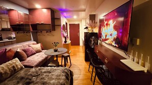 Ein kompakter Wohnbereich mit Sofa, Esstisch, Fernseher und Küchenzeile.