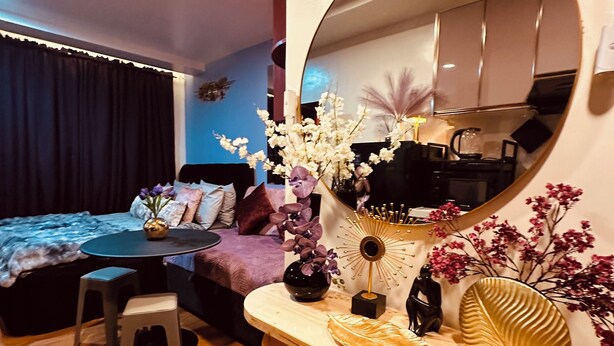 Ein modernes Wohnzimmer mit einem runden Spiegel, einem Holzkonsolentisch, einer Couch, einem Couchtisch und einem Essbereich.