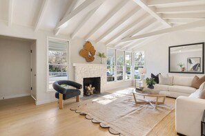 Una sala de estar con chimenea, un sofá, un sillón y un ventanal grande.