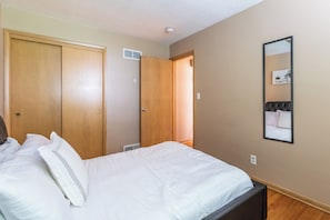 A hotel room with a bed, a wardrobe, a mirror, and a door leading to another room.