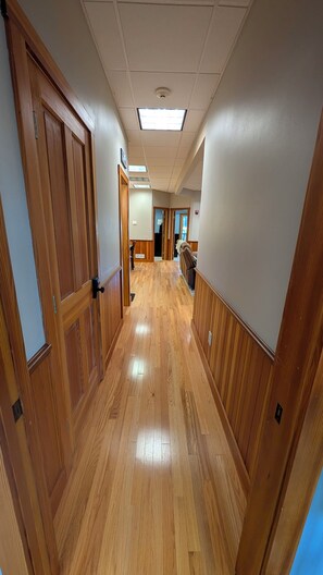 A hallway with wooden paneling, a tiled ceiling, and a view into another room. - 3BR Gilford Condo, Newly Updated, 2 private balconies, 2 min to walk town docks. (Gilford)