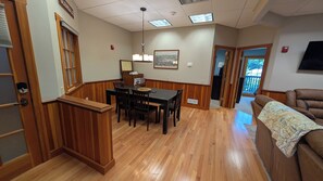 A dining area with a wooden table and chairs, a bench, and a ceiling light fixture.