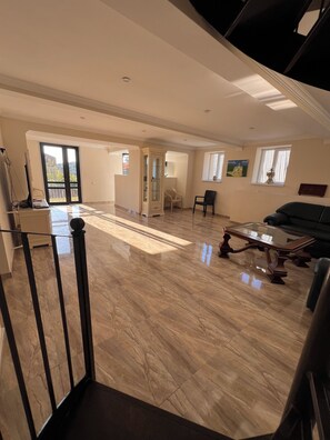 A spacious living area with a high ceiling, a glass coffee table, and a sofa.