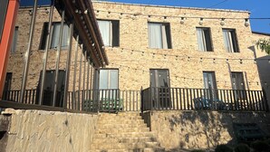 A building with a stone facade, multiple windows, a staircase leading to a balcony, and a pool area. - Happy house (Kutaisi)