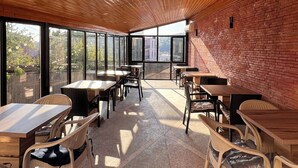 A spacious indoor area with wooden ceiling slats, large windows, and brick walls. - Happy house (Kutaisi)