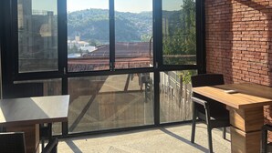 A room with a large window, a wooden ceiling, and a brick wall. - Happy house (Kutaisi)