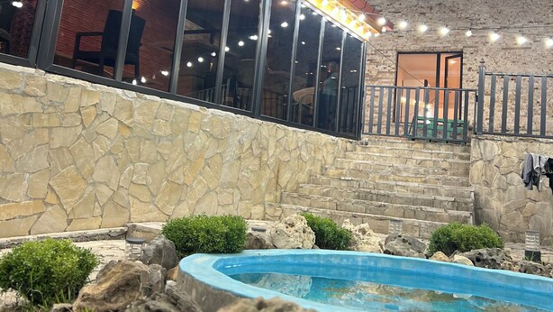 A stone wall, a swimming pool, and string lights. - Happy house (Kutaisi)