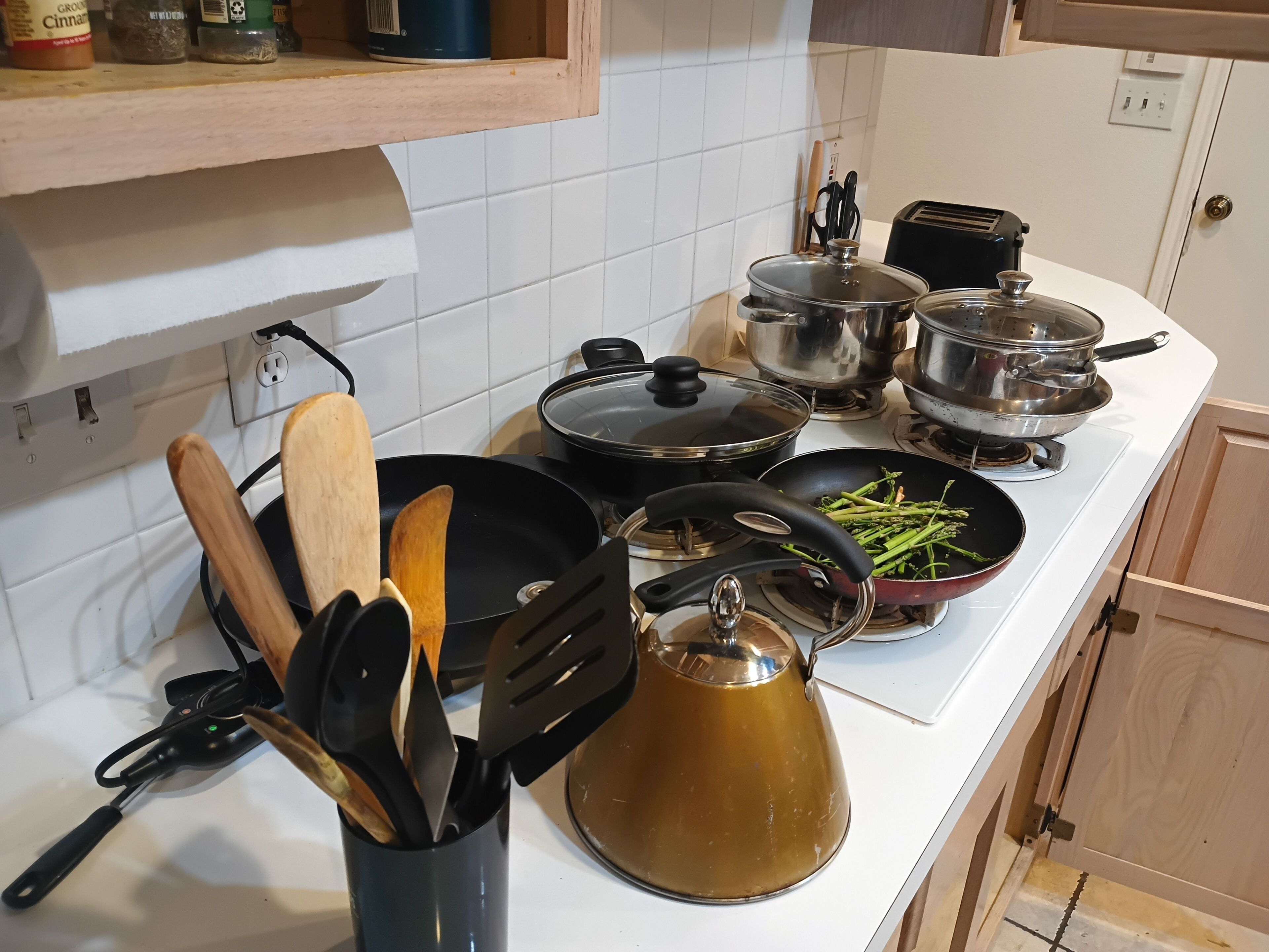 Eine Küche mit Herd, Töpfen, Wasserkocher und verschiedenen Küchenutensilien.