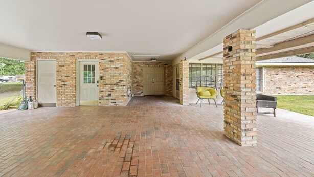 A spacious indoor area with brick walls, a door, and a chair.