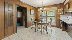 A dining area with a round table, chairs, and a chandelier.