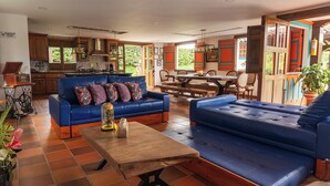 A spacious living area with a blue sofa, a wooden coffee table, and a dining table with chairs. - Country house with pool near Parque del Café - 14 Sleeps -Coffee Region (Montenegro)