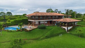 A two-story house with a swimming pool, surrounded by lush greenery. - Country house with pool near Parque del Café - 14 Sleeps -Coffee Region (Montenegro)