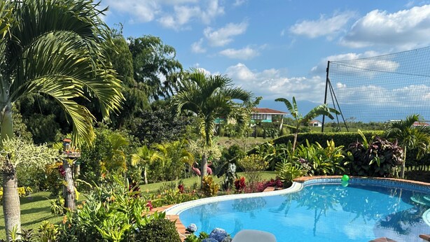 A round metal table with a white plate of food, four coffee mugs, and a tray of flowers. - Country house with pool near Parque del Café - 14 Sleeps -Coffee Region (Montenegro)