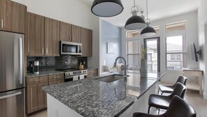 A modern kitchen with granite countertops, stainless steel appliances, and wooden cabinets. - Landing | Beautiful 1BD, Clubhouse (McKinney)