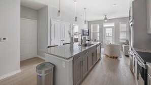 Una cocina moderna con encimeras de granito, electrodomésticos de acero inoxidable y una isla central.