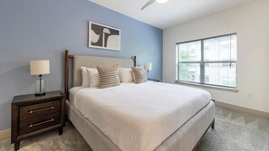 Ein Schlafzimmer mit einem Bett, Nachttischen, einem Fenster und einem Wandbild.