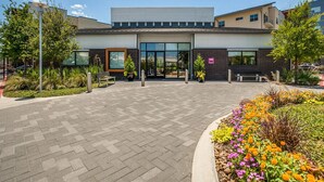 Ein modernes Gebäude mit einer großen Garagentür, einer Bank und einem Blumenbeet mit verschiedenen Pflanzen und Blumen.
