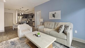 Ein modernes Wohnzimmer mit Sofa, Couchtisch und Essbereich mit einem Stuhl.